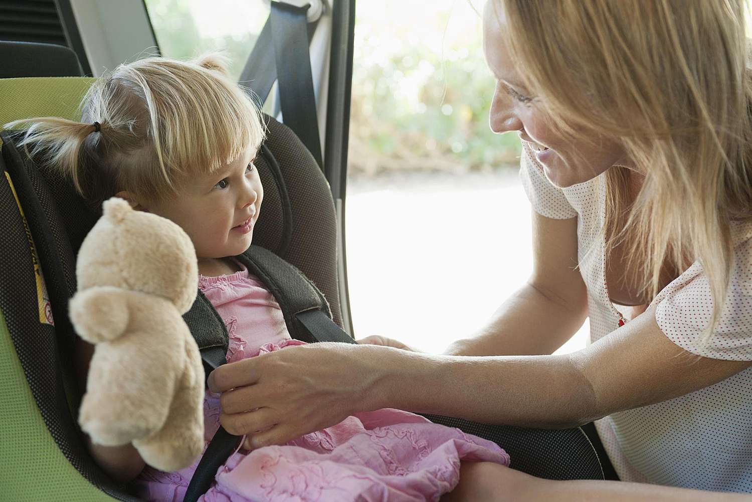 Mãe prendendo a menina no assento do carro