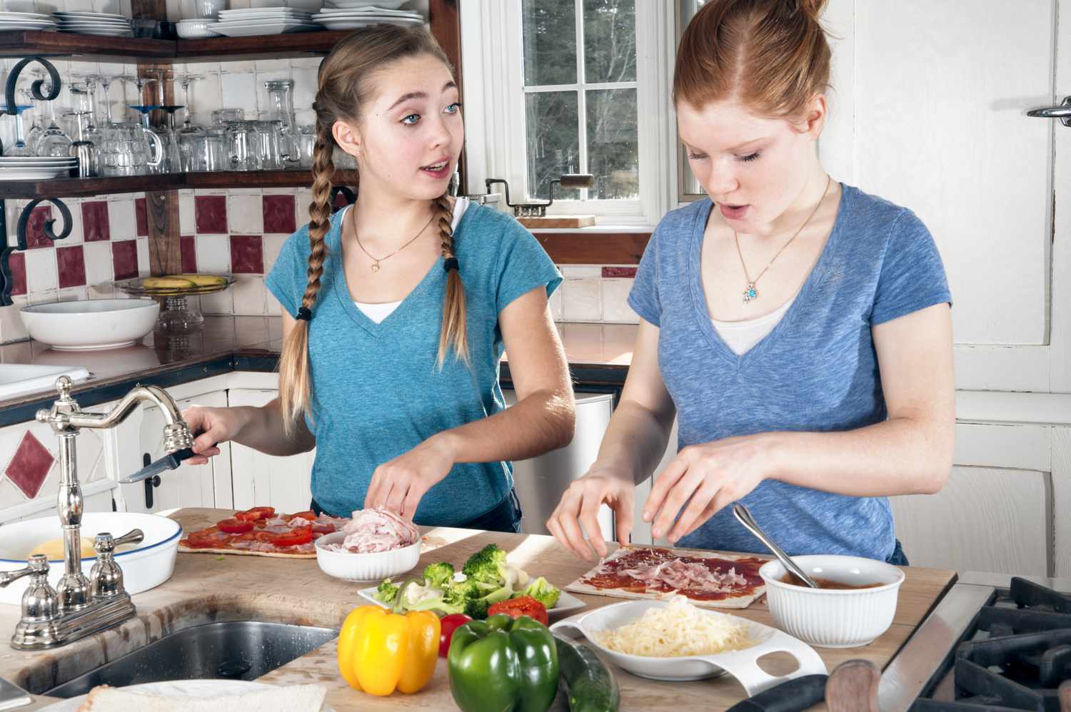 Adolescentes fazendo pizzas de pão achatado na cozinha